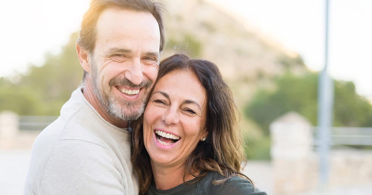 Middle-aged white couple in embrace and smiling