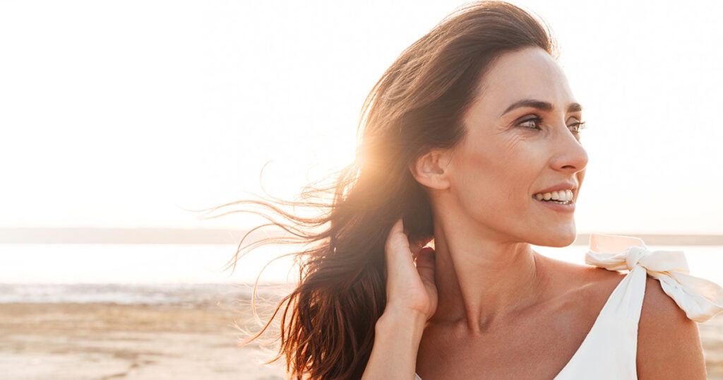 Woman at beach, looking over shoulder and smiling