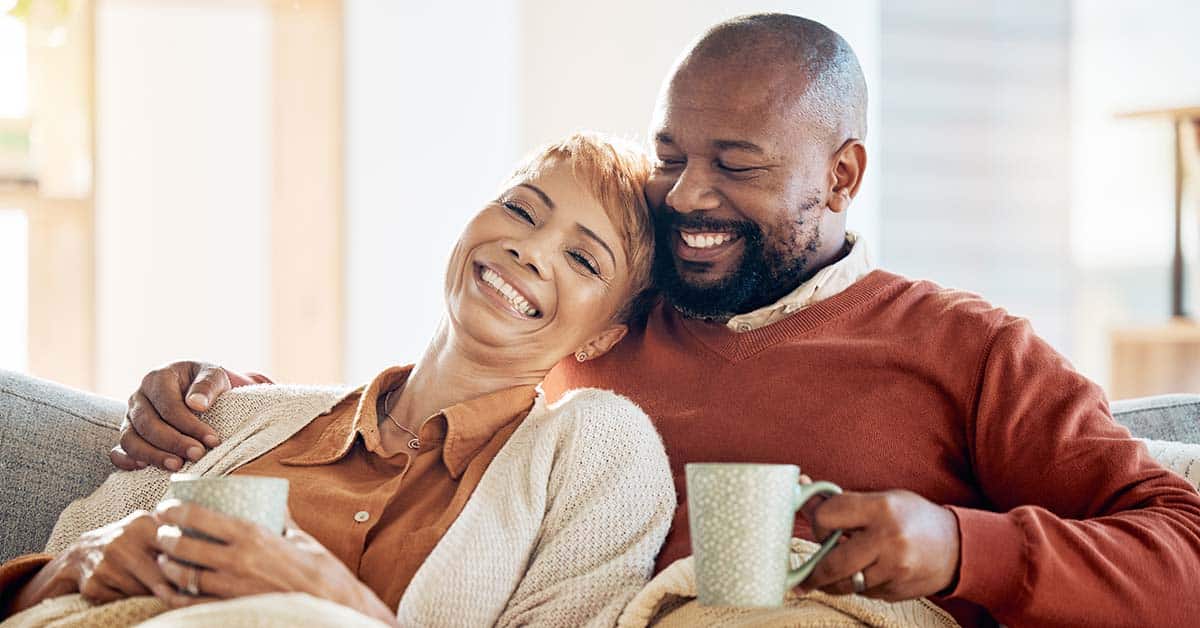 older couple on couch drinking tea and smiling