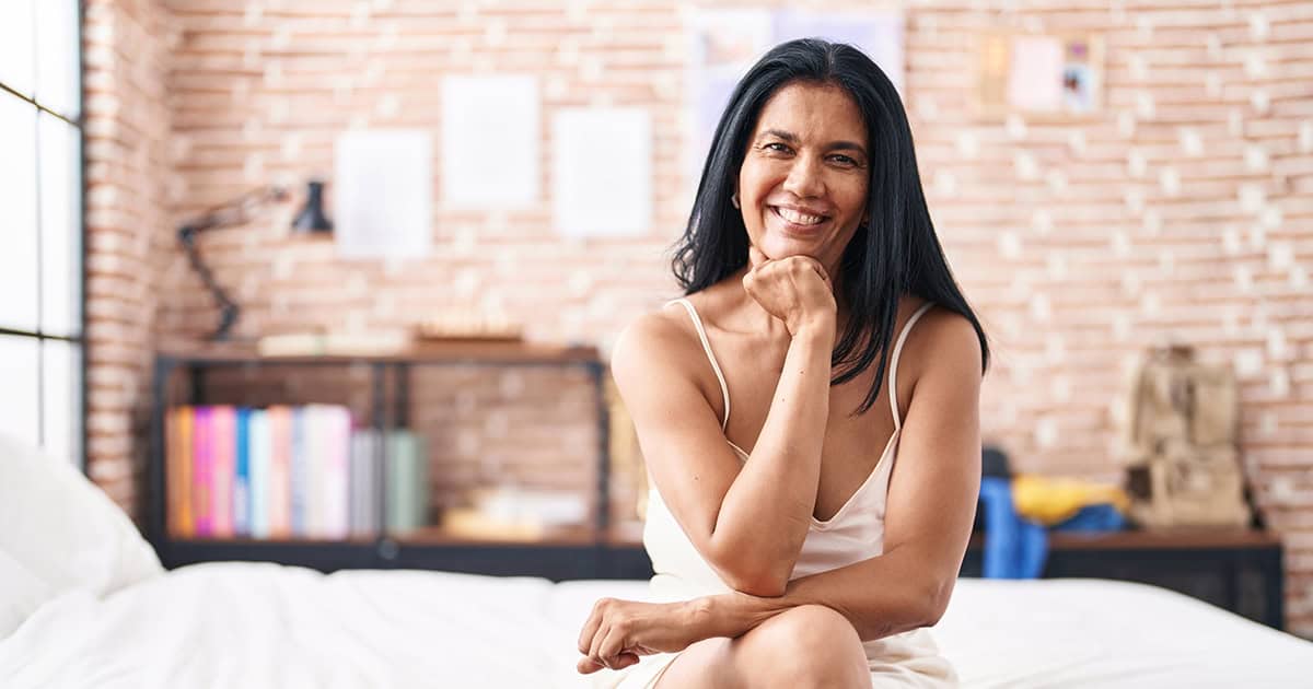 vaginal dryness remedies woman sitting on edge of bed smiling