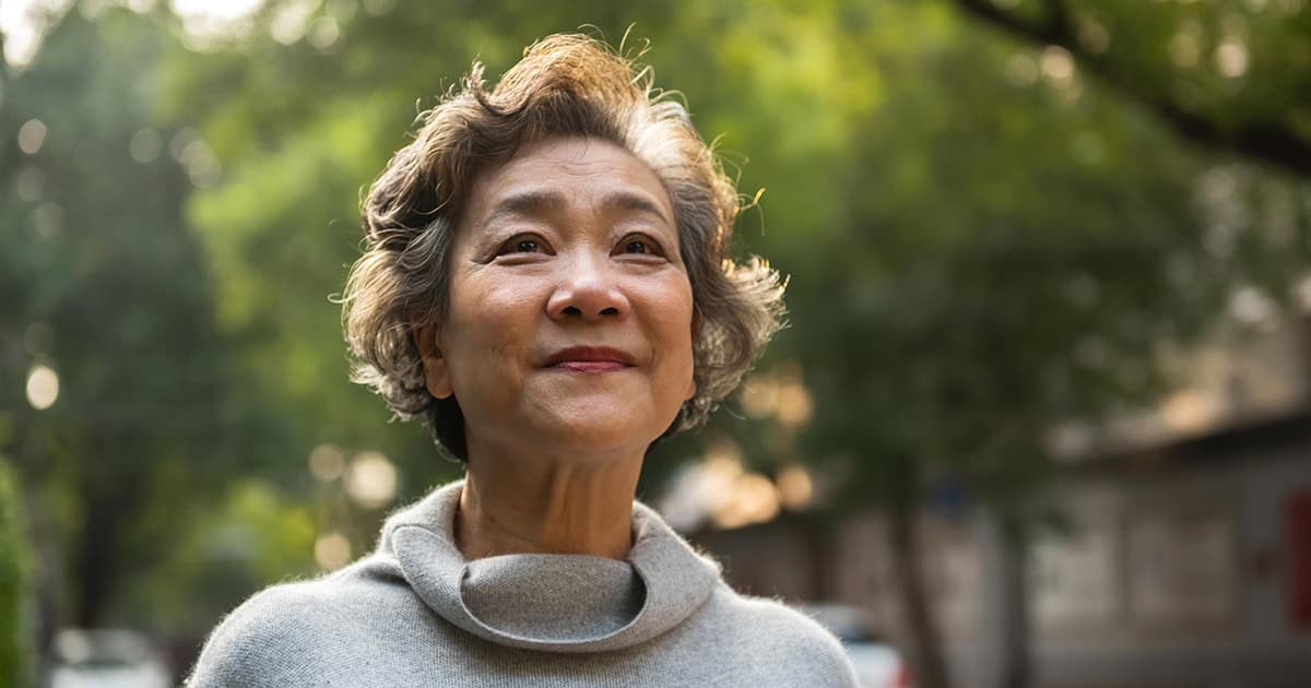 Asian older short haired woman with hopeful look on face